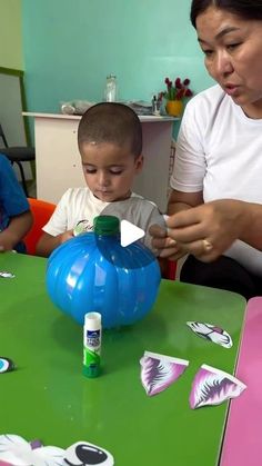 a woman sitting at a table with a young boy playing with an inflatable ball