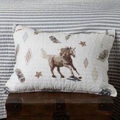 a pillow with a horse on it is sitting on a trunk in front of a bed