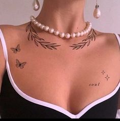 a woman with tattoos on her chest wearing pearls