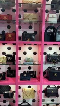 a display case filled with lots of purses and handbags on top of pink shelves