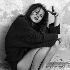 black and white photograph of a woman sitting on the ground with her hands behind her head