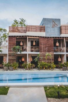 an outdoor swimming pool in front of a building with wooden balconies on it