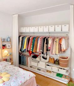 an organized closet with clothes and baskets on the shelves, next to a bed in a bedroom