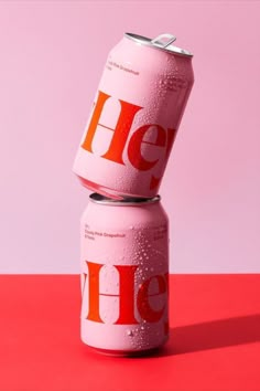 two cans of heine are stacked on top of each other in front of a pink background