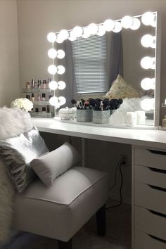 a white vanity with lights on it and a chair in front of the mirror that is lit up