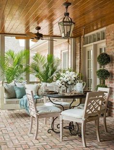 an outdoor patio with chairs, table and potted plants