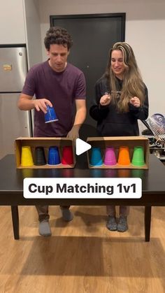 a man and woman standing in front of a table with cup matching items on it