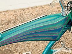 a close up view of the handlebars on a green and blue bike with pink stripes