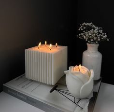 two white candles sitting on top of a book