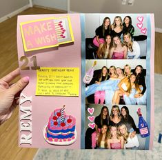 a hand holding up a pink birthday card with pictures of people and a cake on it