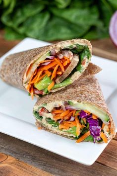 two wraps filled with veggies on top of a white plate