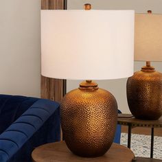 two brown vases sitting on top of a table next to a blue couch and lamp