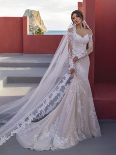 a woman in a wedding dress with a veil on her head standing next to stairs