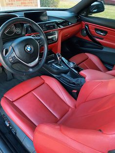 the interior of a bmw car with red leather seats and steering wheel, including center console