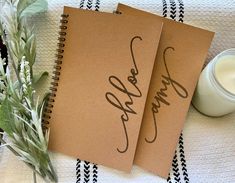 two notebooks with the word love written on them next to a jar of milk