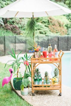 a bar cart with pineapples, pineapples and bottles on it next to a pool