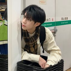 a young man wearing glasses sitting in a basket