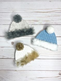 three knitted hats with fur pom - poms on white wood planks