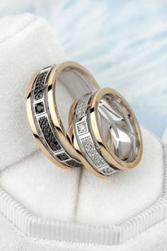 two wedding rings with black and white diamonds on top of each other in a ring box