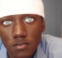 a close up of a person wearing a hat and looking at the camera with blue eyes