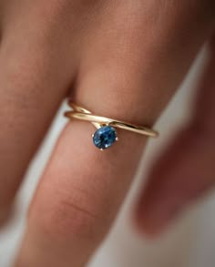 a woman's hand with a gold ring and blue stone on the middle finger