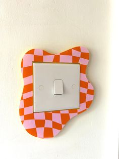 an orange and pink light switch cover on a wall