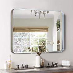 a bathroom sink with a mirror above it and a vase on the counter next to it