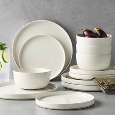 white dishes are stacked on top of each other with fruit in the bowl at the center