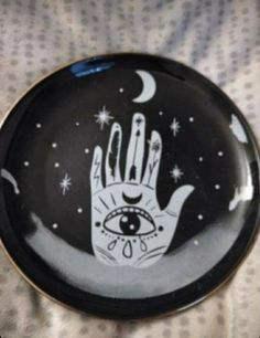 a black and white plate with an image of a hand reaching for the moon on it