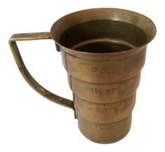 an old brass measuring cup with two sides and the numbers twenty seven on each side