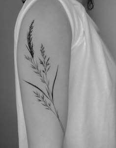 a black and white photo of a woman's arm with a plant tattoo on it