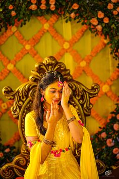 a woman in yellow dress sitting on a chair with her hands clasped to her face