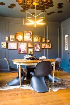 a dining room with blue walls and pictures hanging on the wall above the wooden table