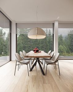 a dining room table surrounded by chairs and a large window with trees in the background