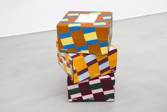 three colorful boxes stacked on top of each other in the middle of an empty room