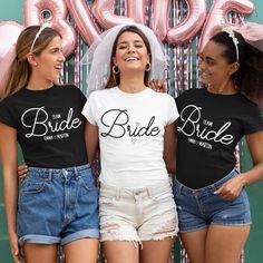 three women standing next to each other in front of pink balloons and the words bride on their shirts