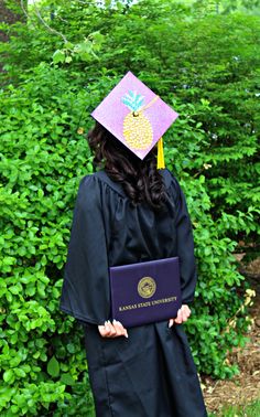 a person wearing a graduation cap and gown with a pineapple embroidered on the front