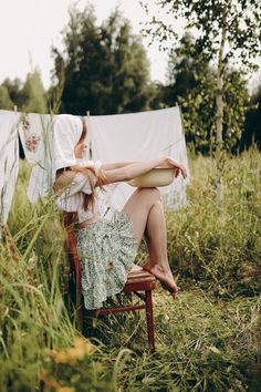 a woman is sitting on a chair in the grass