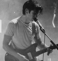 a young man playing guitar while singing into a microphone