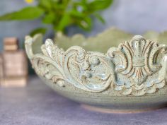 a white bowl sitting on top of a table next to a vase with flowers in it