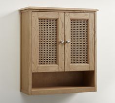 a wooden cabinet with perfored doors on the front and sides, against a white wall