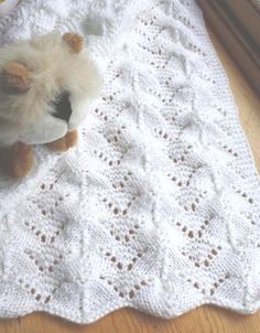 a teddy bear sitting on top of a white crocheted blanket next to a window