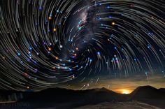 star trails in the night sky over mountains