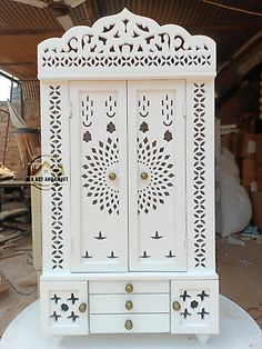 a white cabinet sitting on top of a table next to boxes and other items in the background