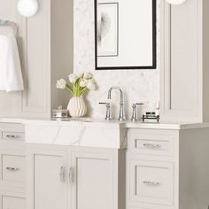 a white bathroom with marble counter tops and double sinks