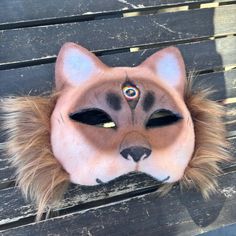 an animal mask is sitting on a wooden bench