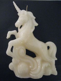 a white horse statue sitting on top of a black table next to a light bulb