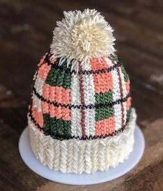 a knitted hat sitting on top of a white plate next to a wooden table