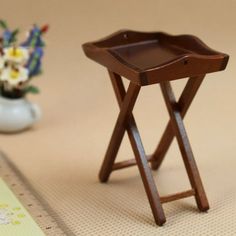 a small wooden tray on a table next to a vase with flowers