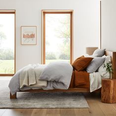 a bedroom with white walls and wooden furniture, including a bed that has two pillows on it